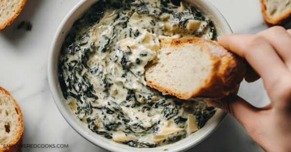 dipping bread in spinach artichoke dip